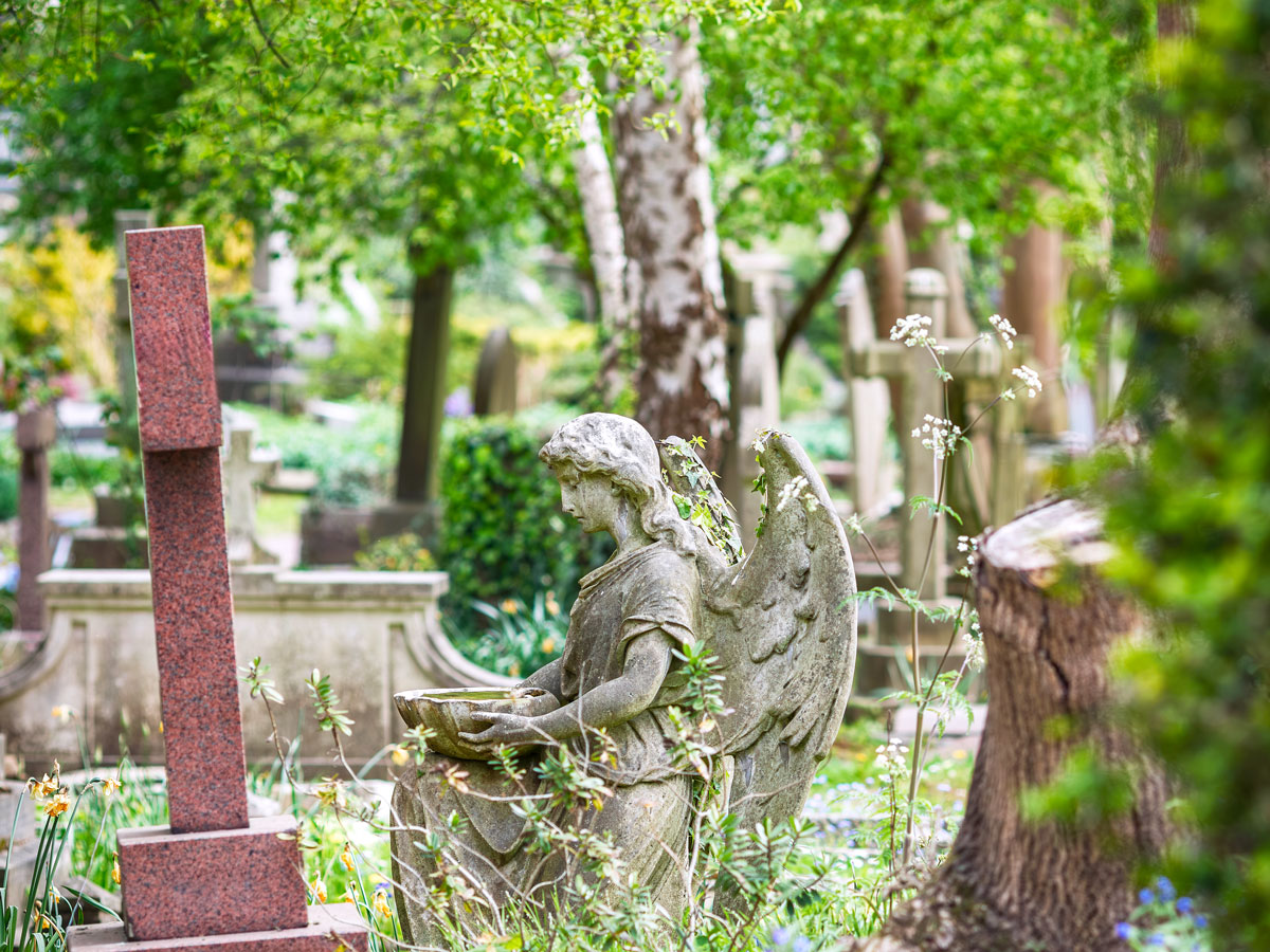Statue of angel in front of tomb at Highgate Cemetery in London, England