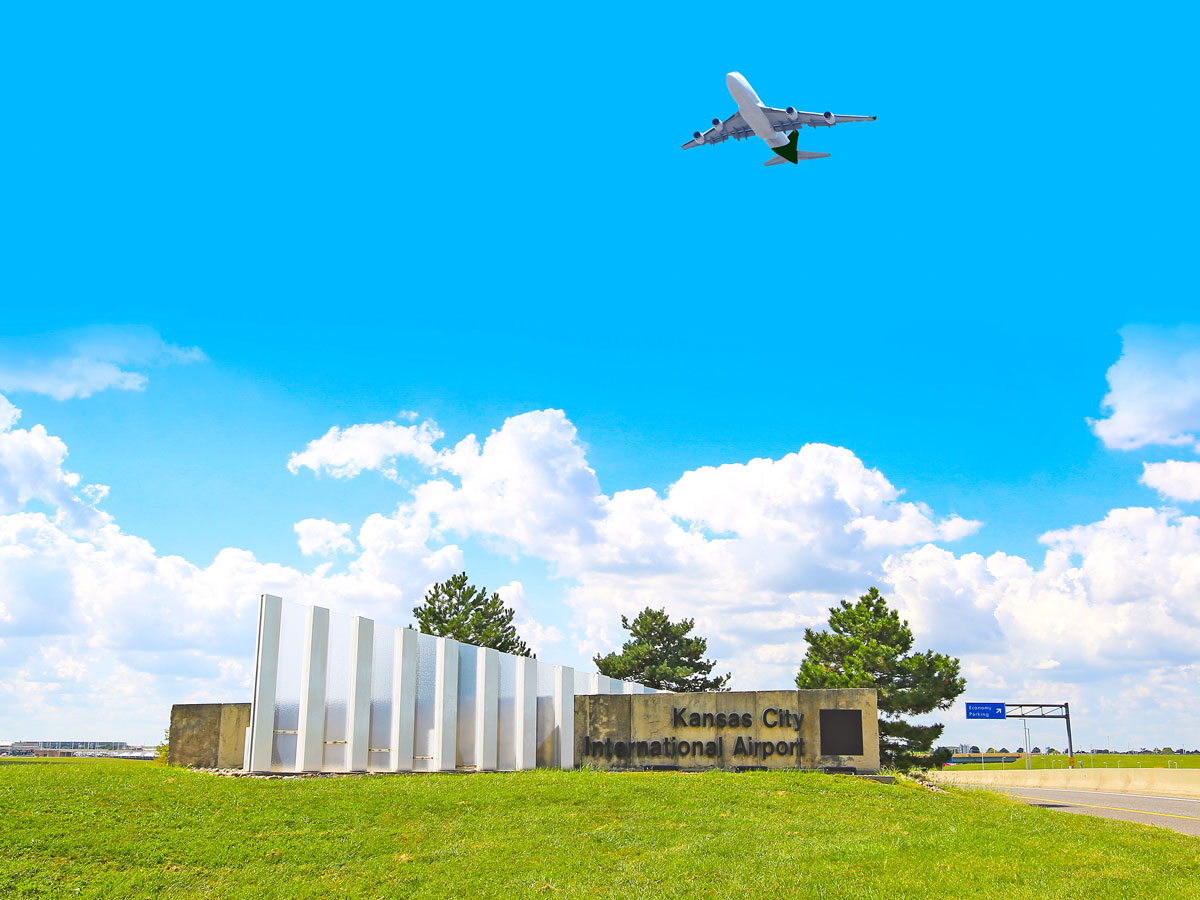 Jet taking off over sign for Kansas City International Airport