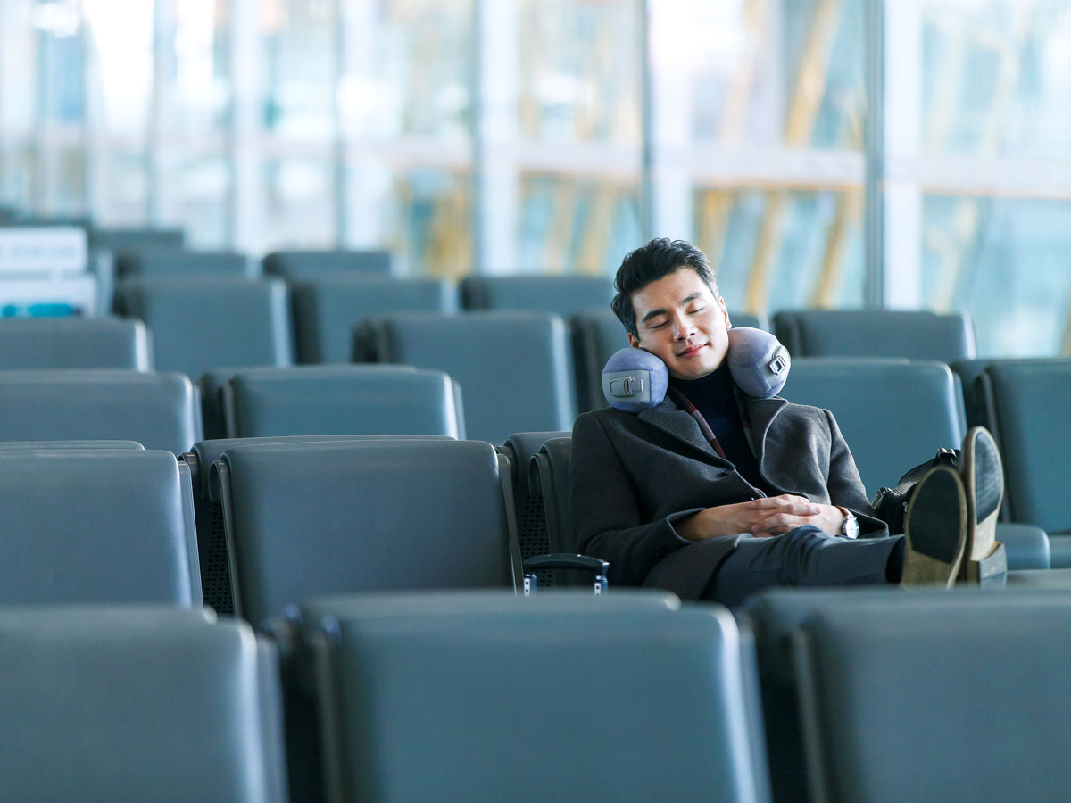 Traveler sleeping with neck pillow in airport terminal