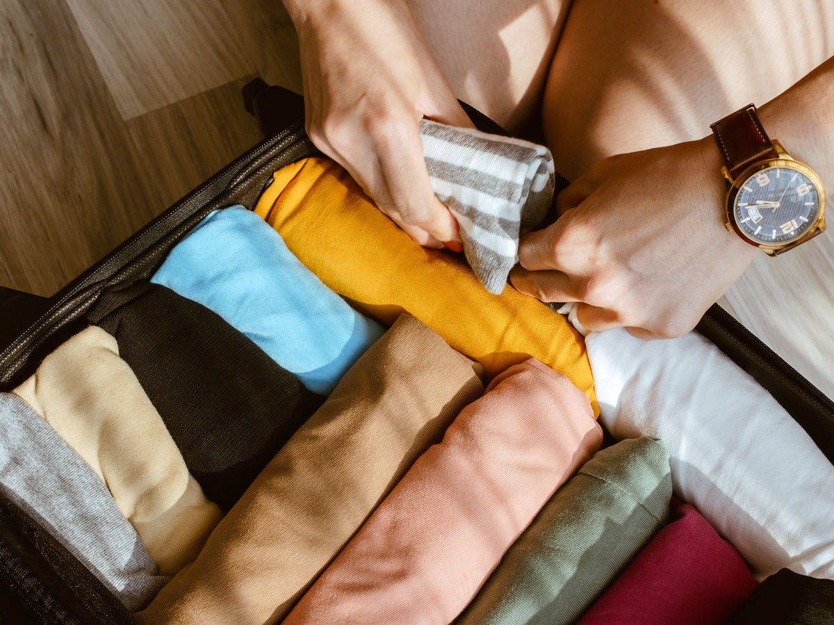 Traveler packing clothes in suitcase