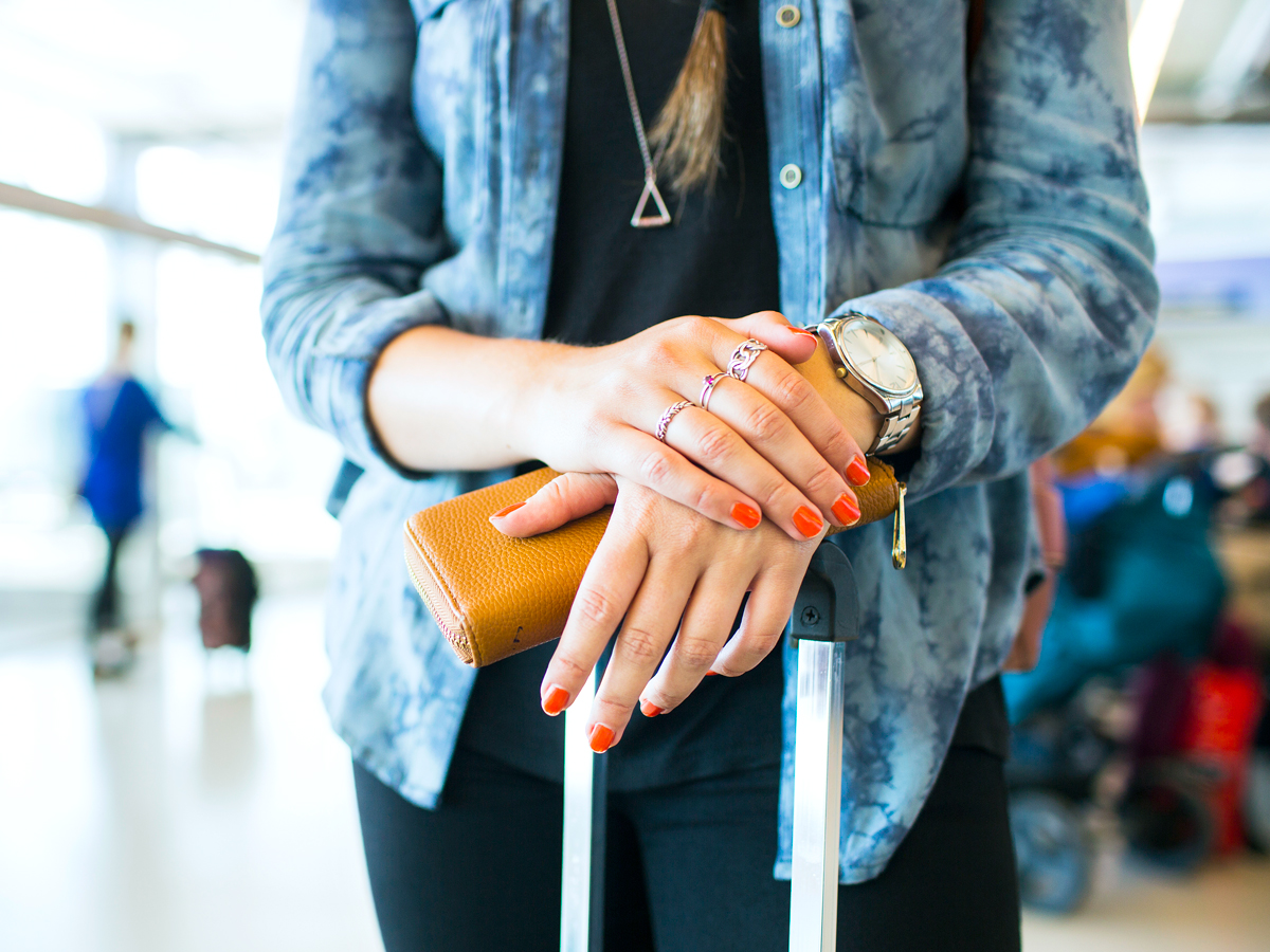 Person resting hands on suitcase handle