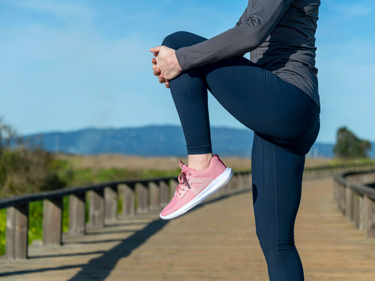Person lifting knee to chest on walking path