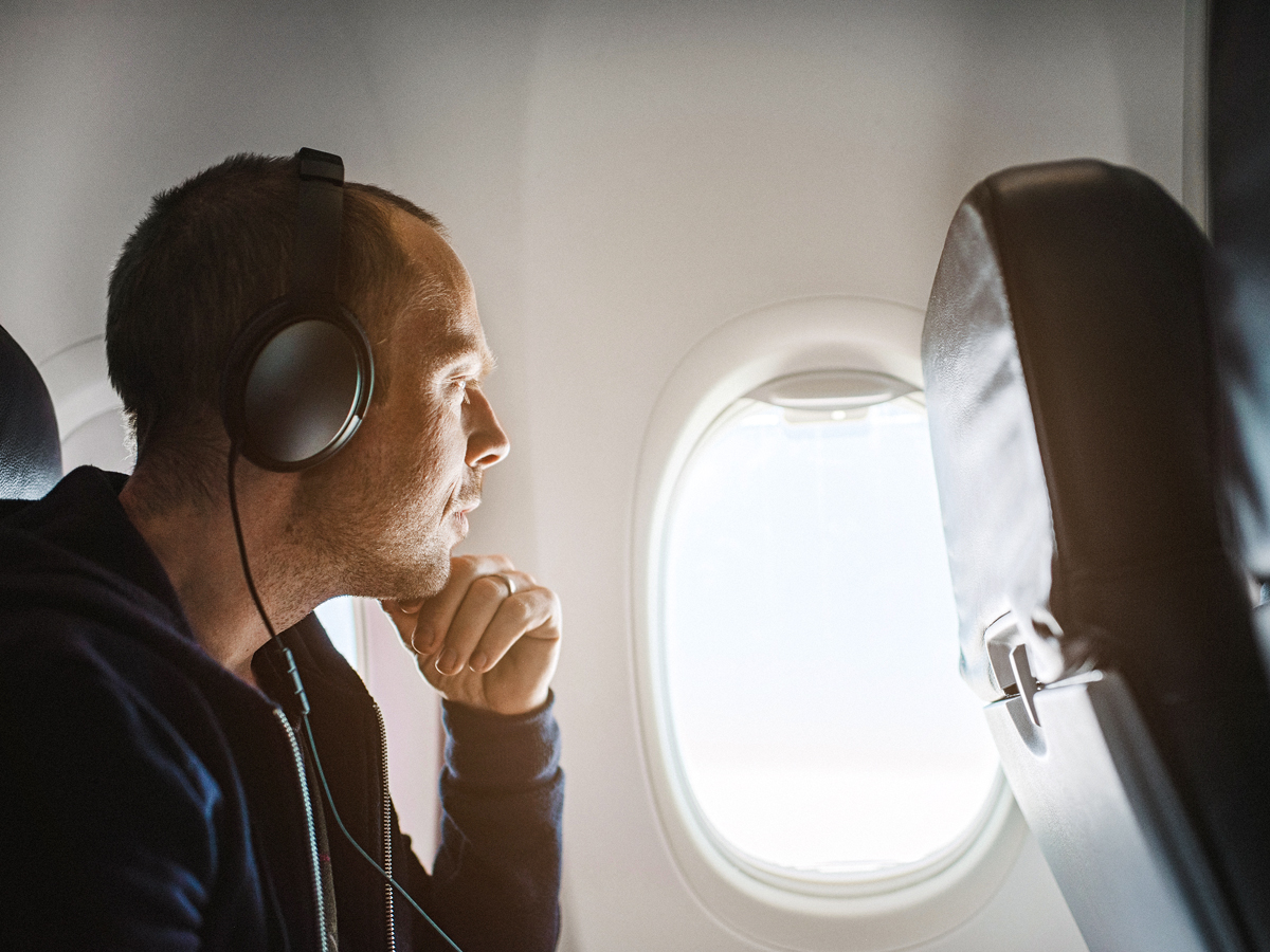 Passenger wearing headphones and gazing out airplane window