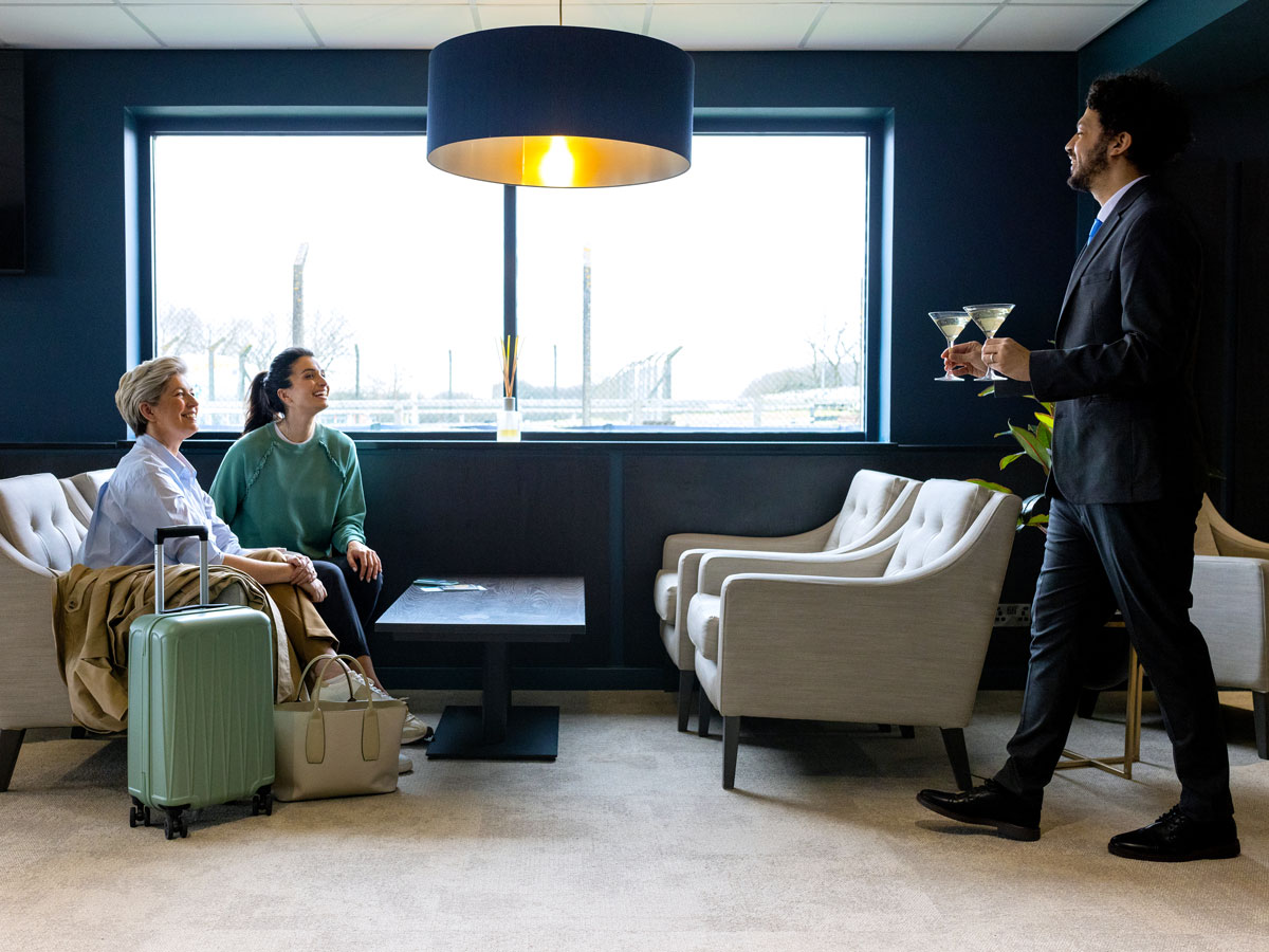 Employee serving passengers drink in airport lounge