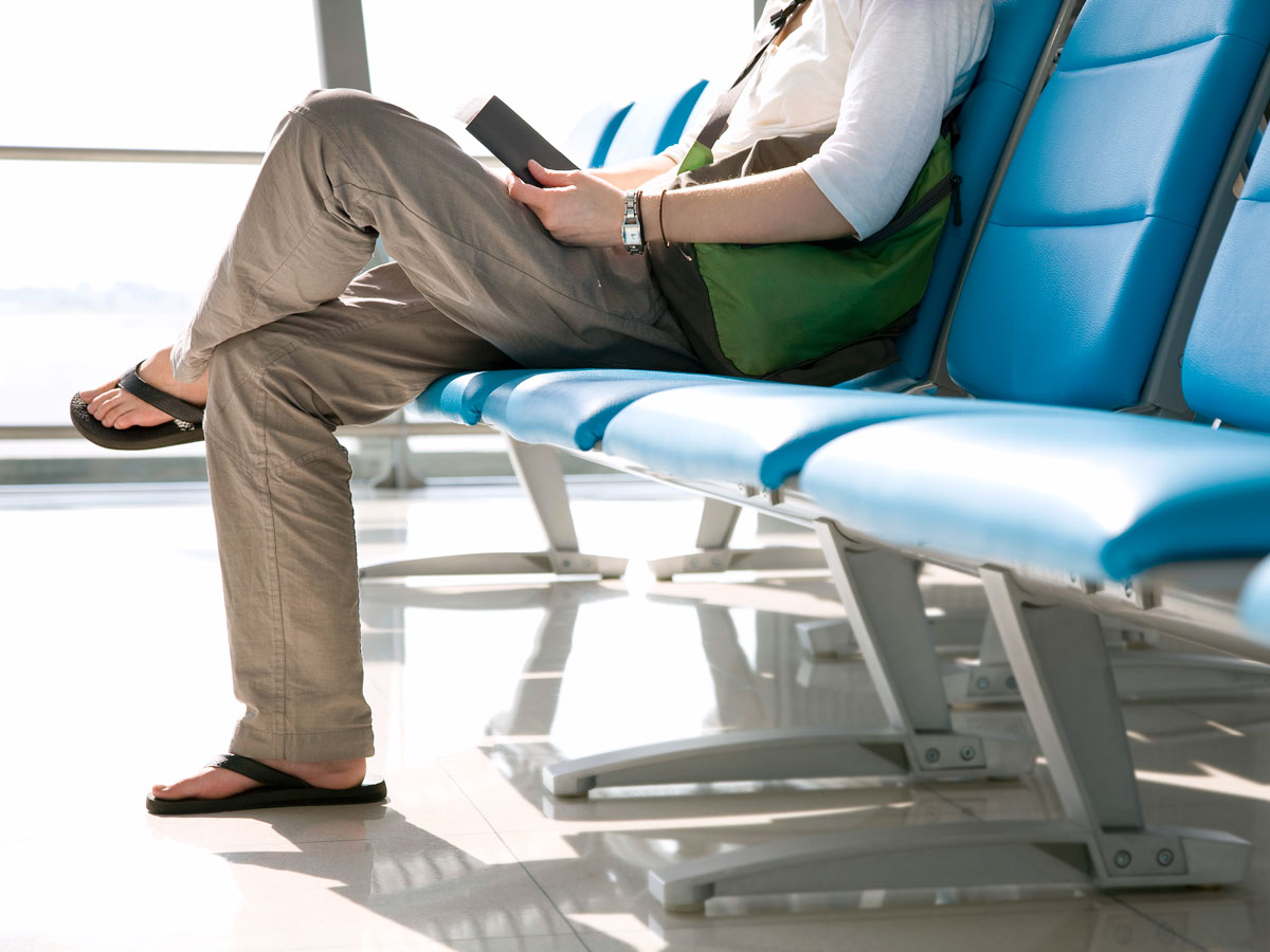 Airline passenger sitting at gate wearing sandals