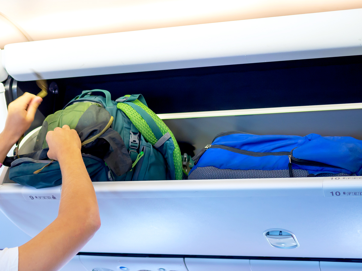 Traveler stowing bags in aircraft's overhead bin