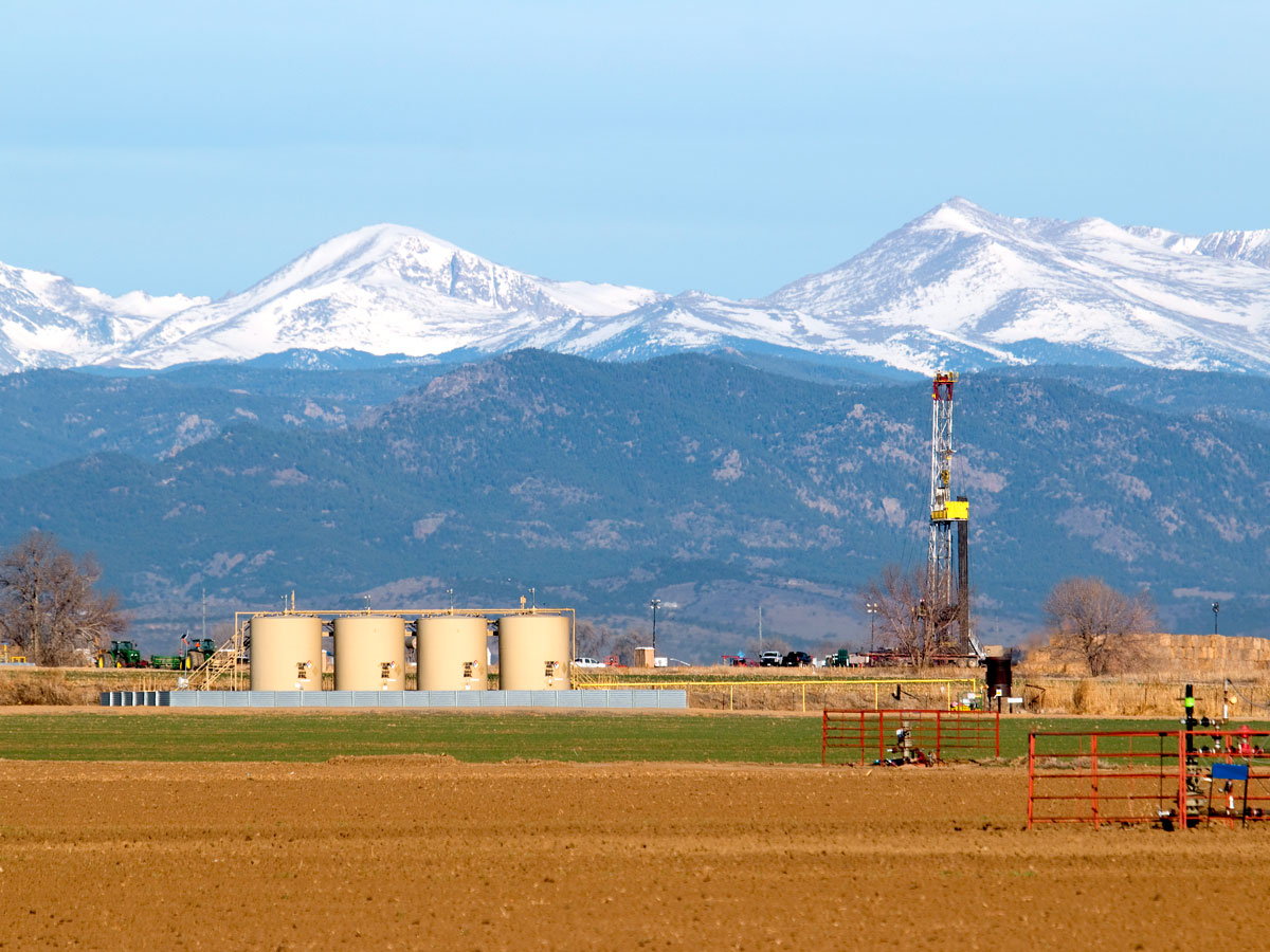 Oil drill in front of snow-covered peaks in Colorado
