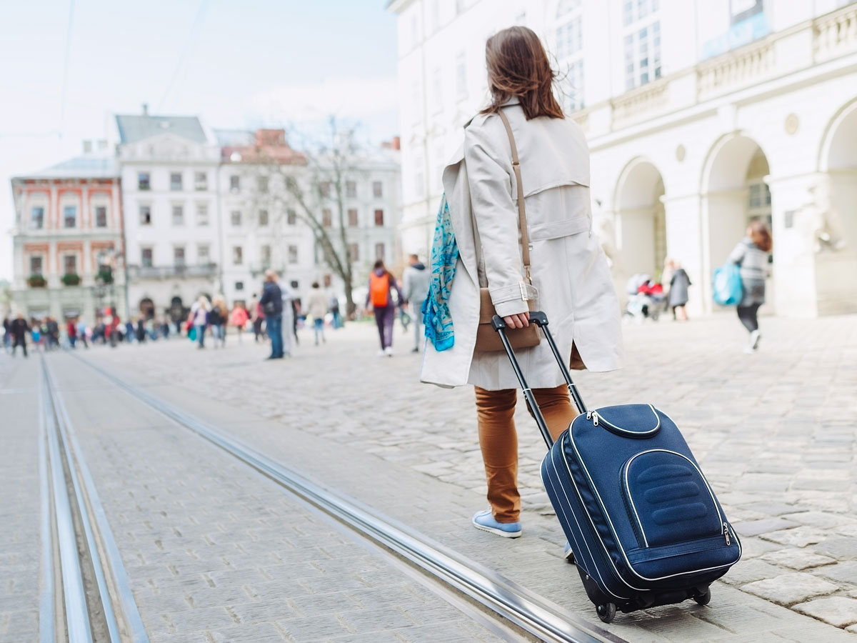 Traveler rolling suitcase through city square
