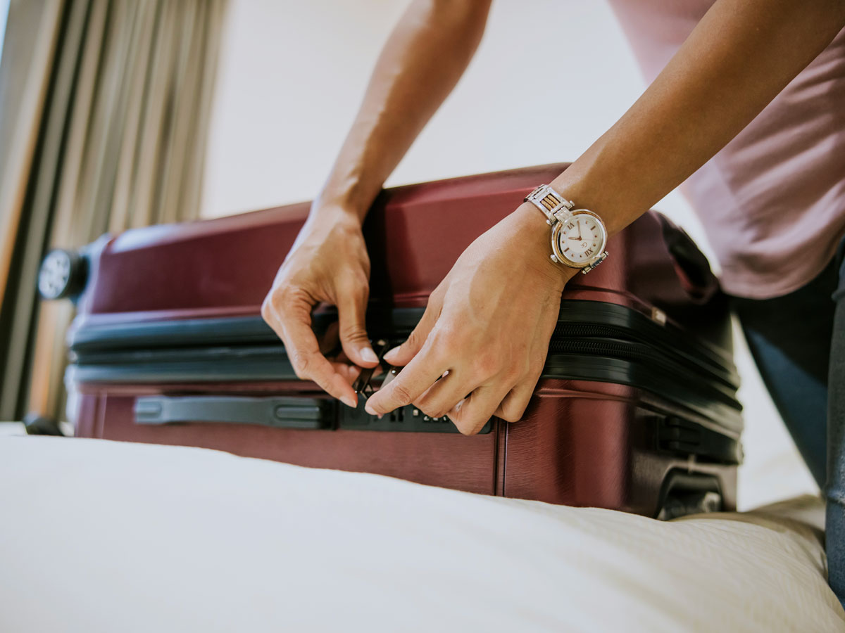 Person locking luggage on bed