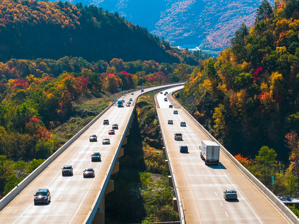 Aerial view of automobiles on the Pennsylvania Turnpike beside fall foliage