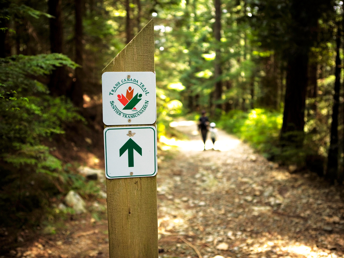 Trail marker and hikers on the Trans Canada Trail