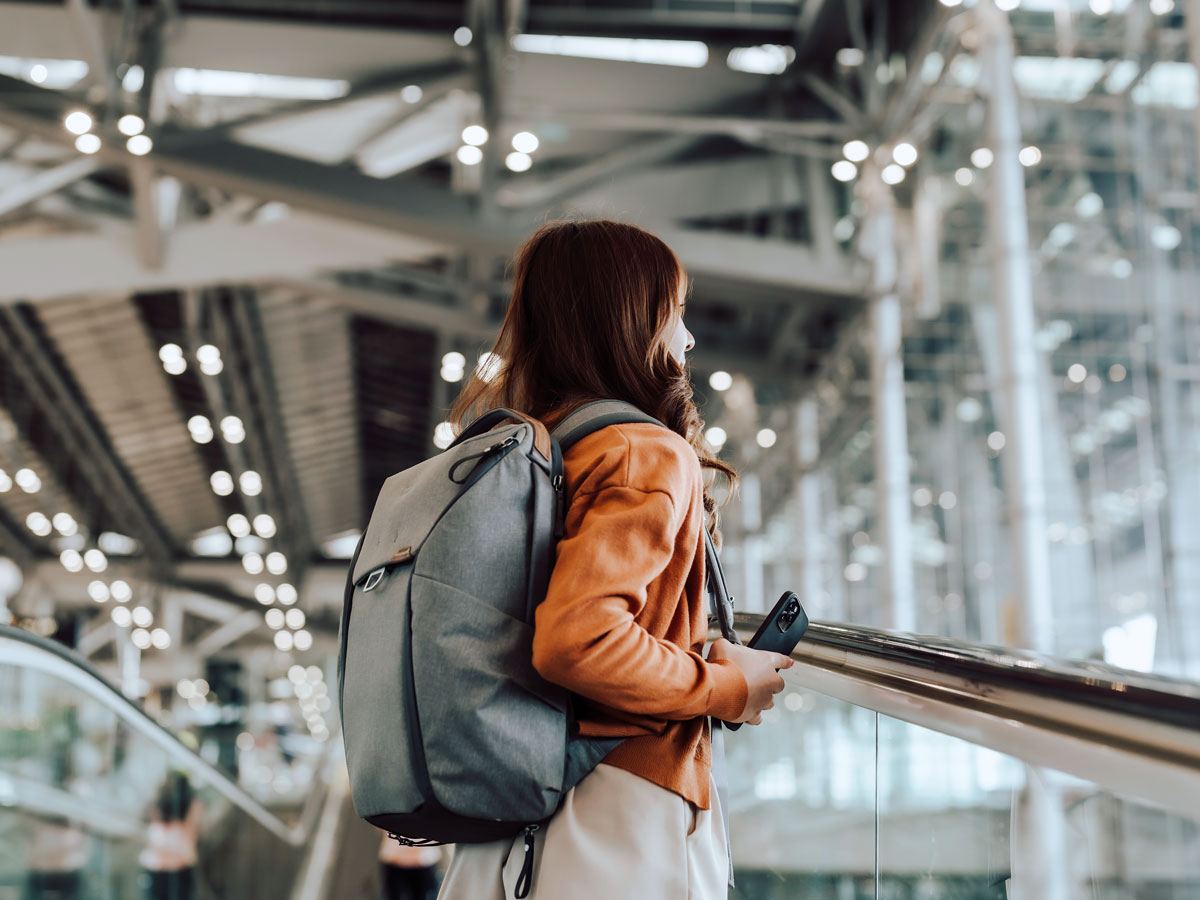 Traveler with backpack on escalator in airport