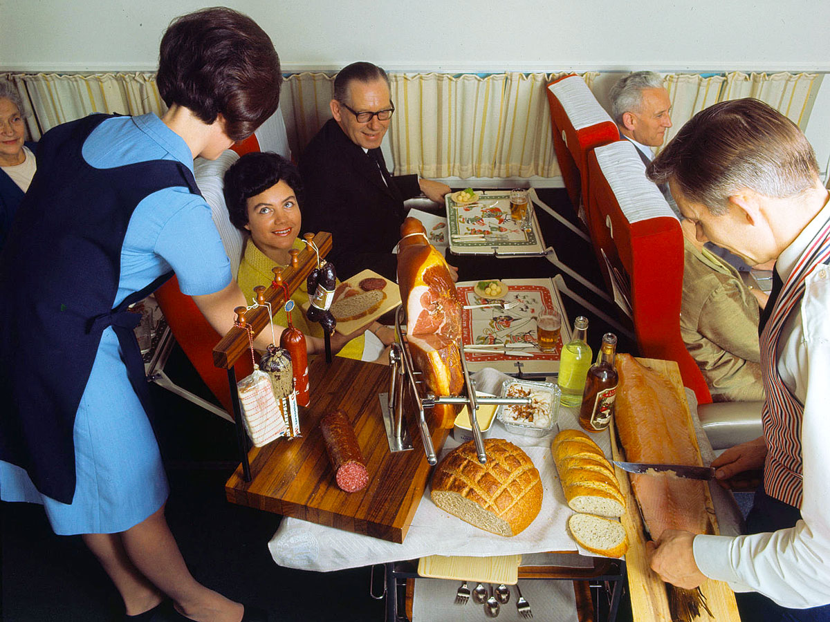 Historical image of flight attendants carving food for passengers in flight