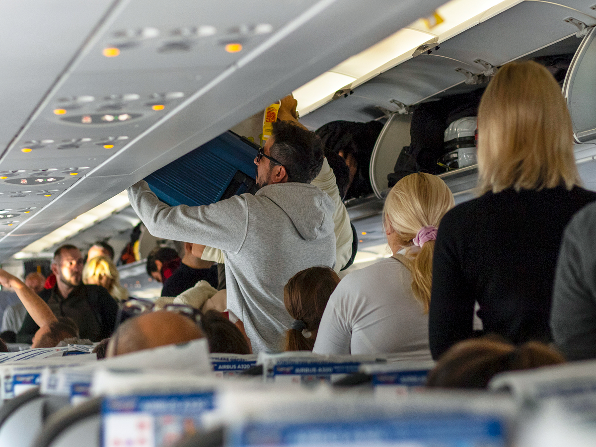 Passengers stowing bags as they board a plane