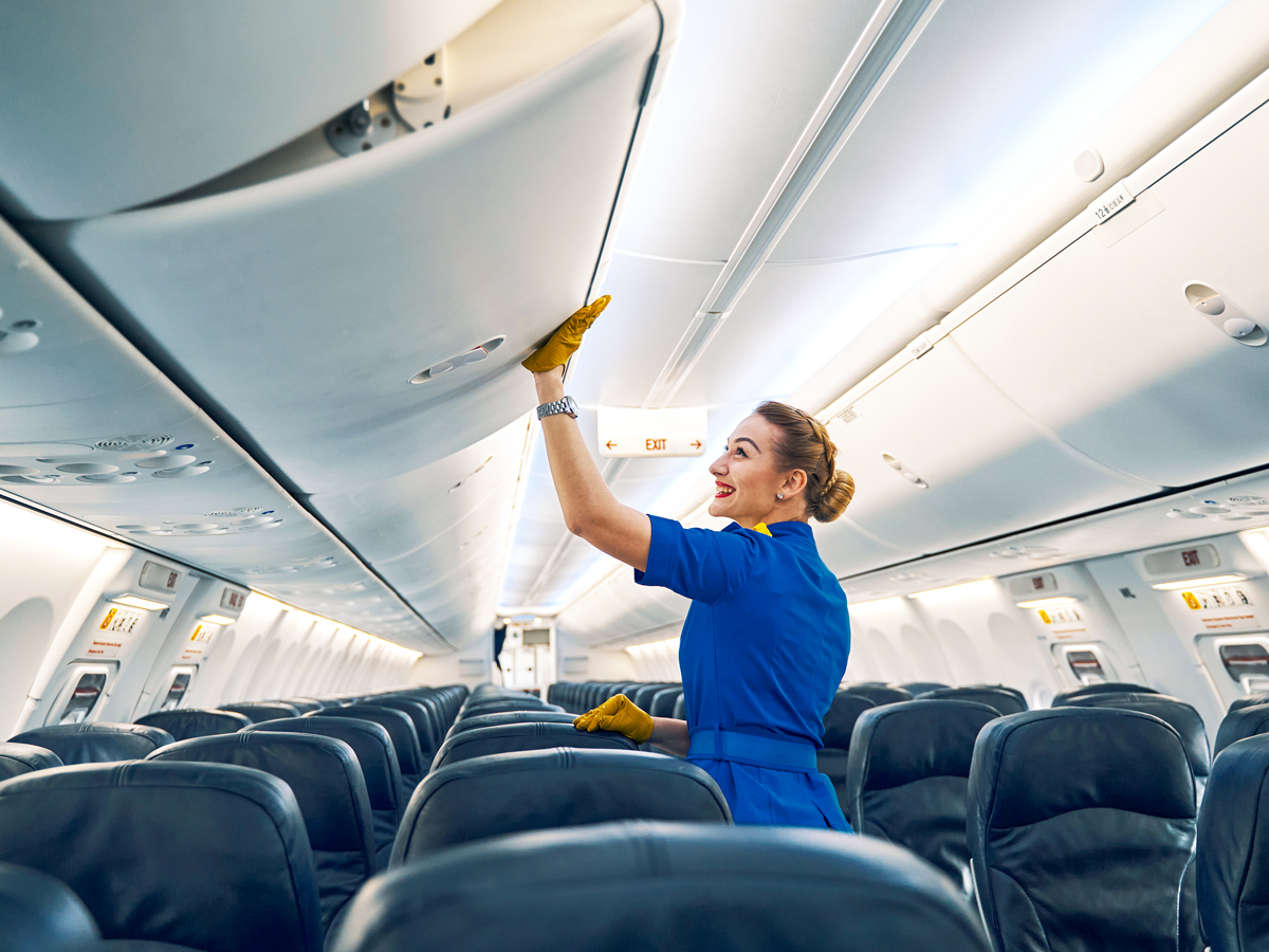 Flight attendant closing aircraft overhead bin