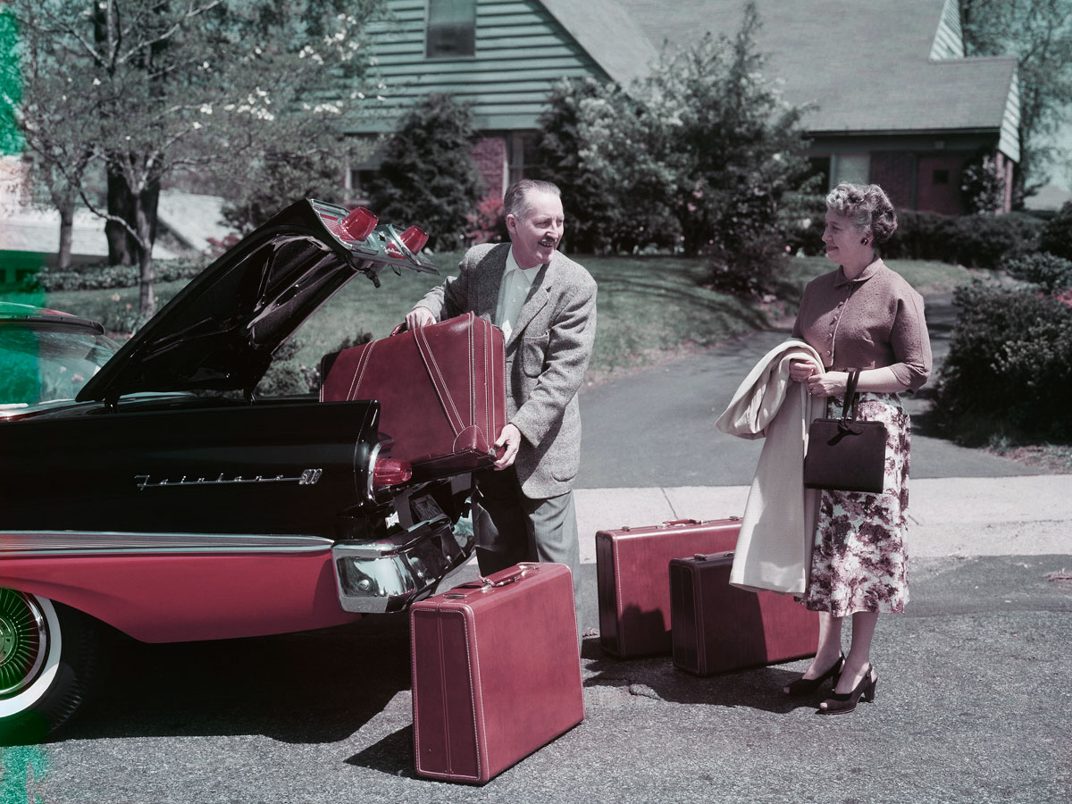 Man and woman packing trunks into car in 1950s