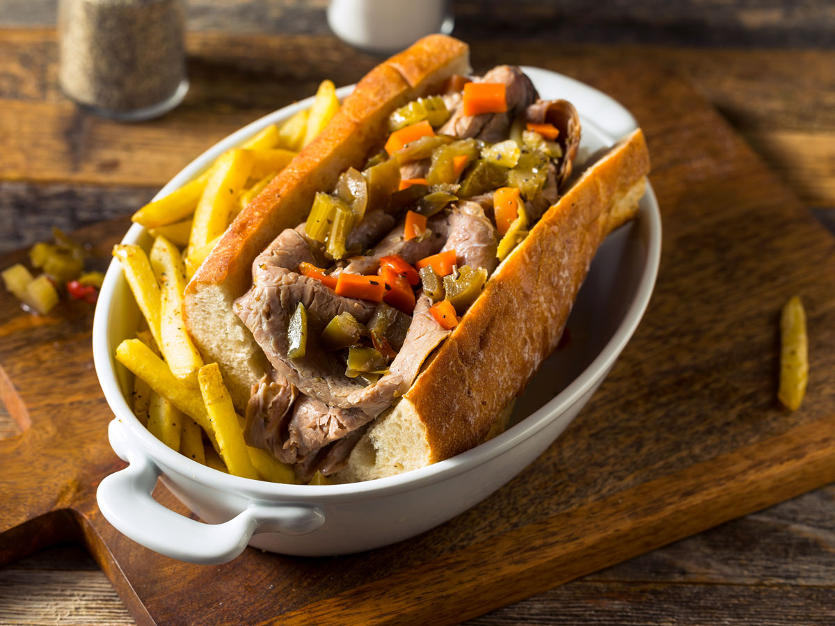 A casserole dish with an Italian beef sandwich and fries