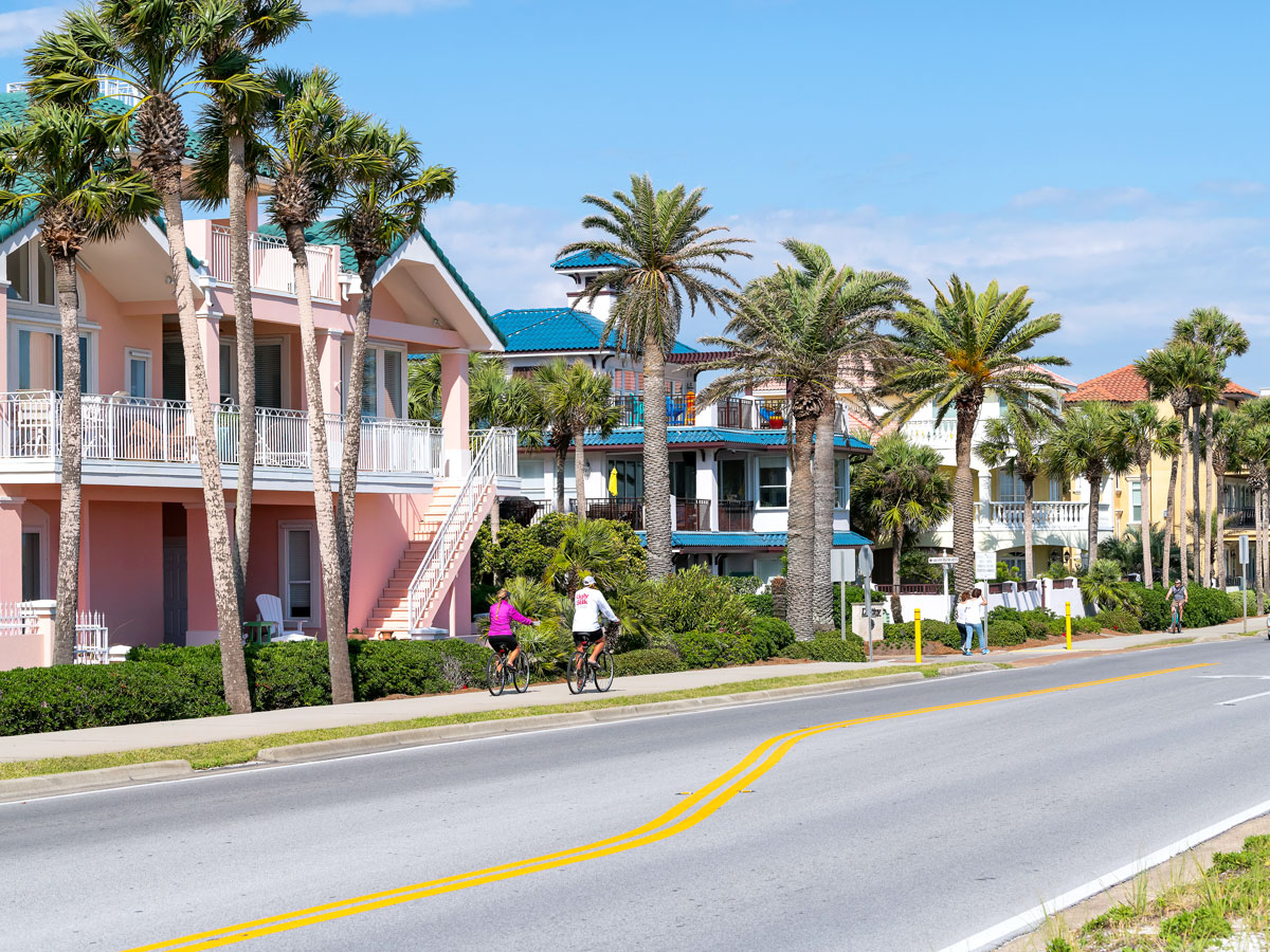 Bikers and pedestrians in front of homes and palm trees in Fort Walton Beach, Florida