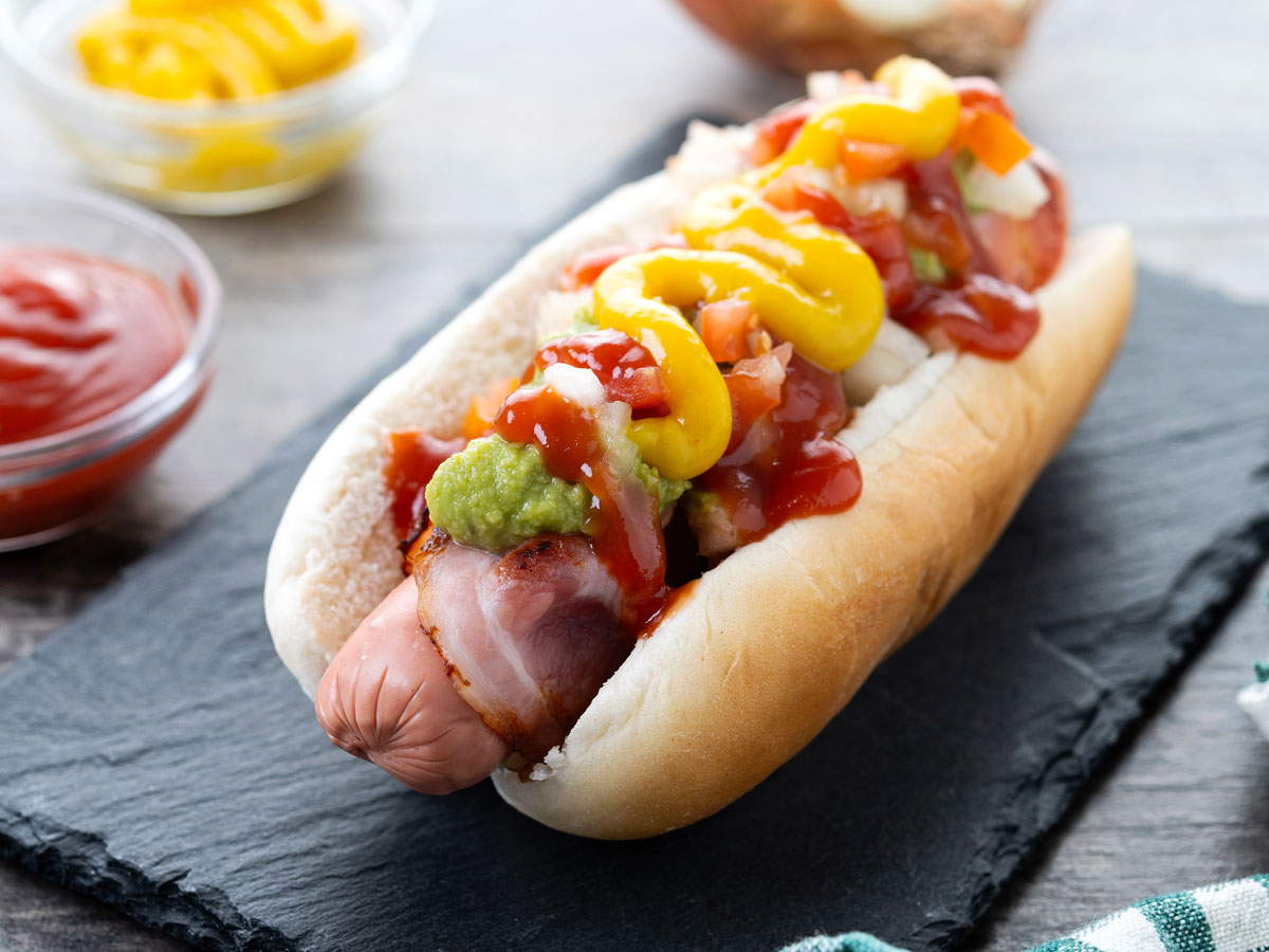 A Sonoran hot dog with condiments on a countertop