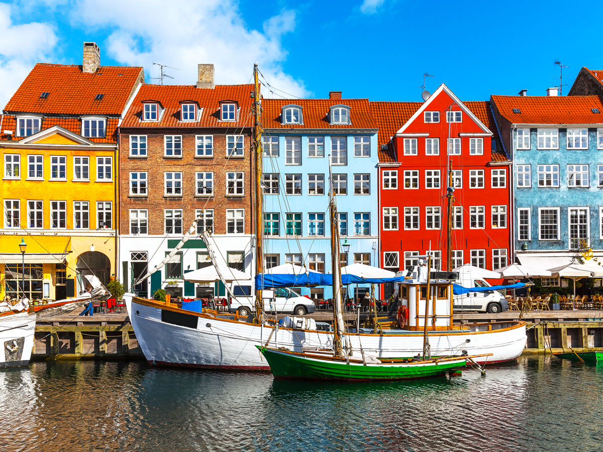 Boats moored in front of colorful homes in Nyhavn, Copenhagen, Denmark