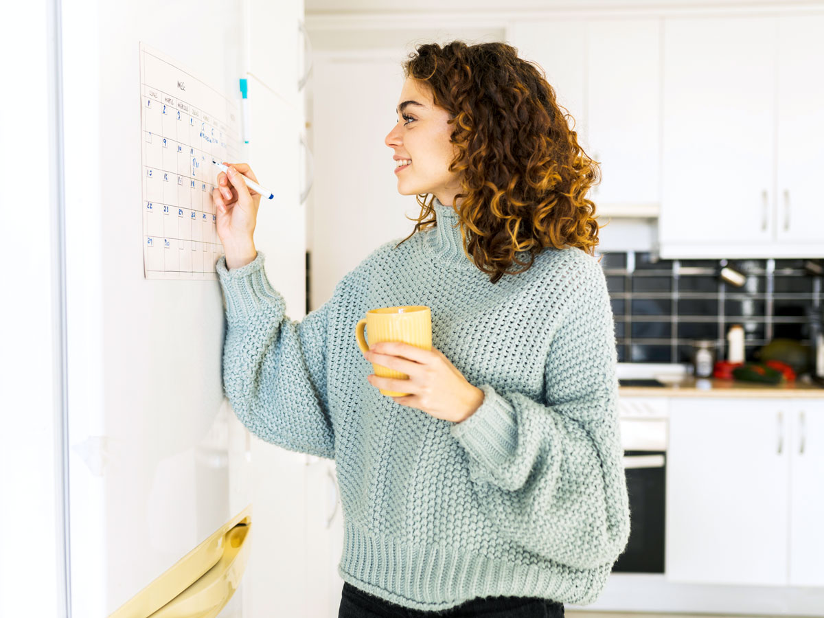 Person marking calendar in kitchen