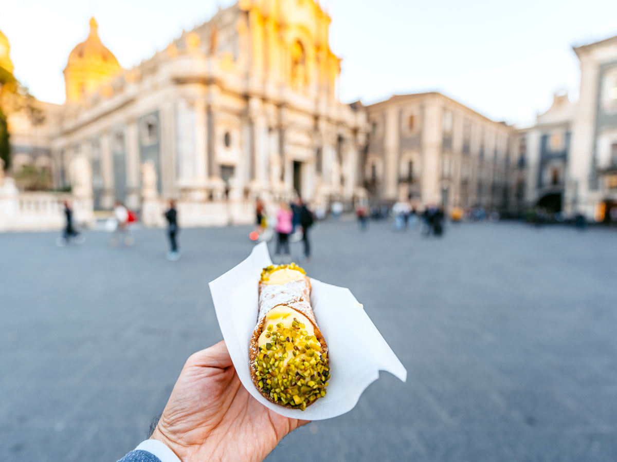 Person holding cannoli in square of Catania, Sicily