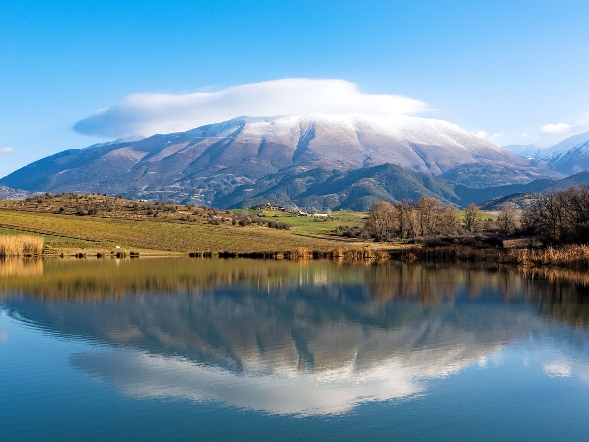 Clouds obscuring peak of Mount Olympus, with reflection on lake