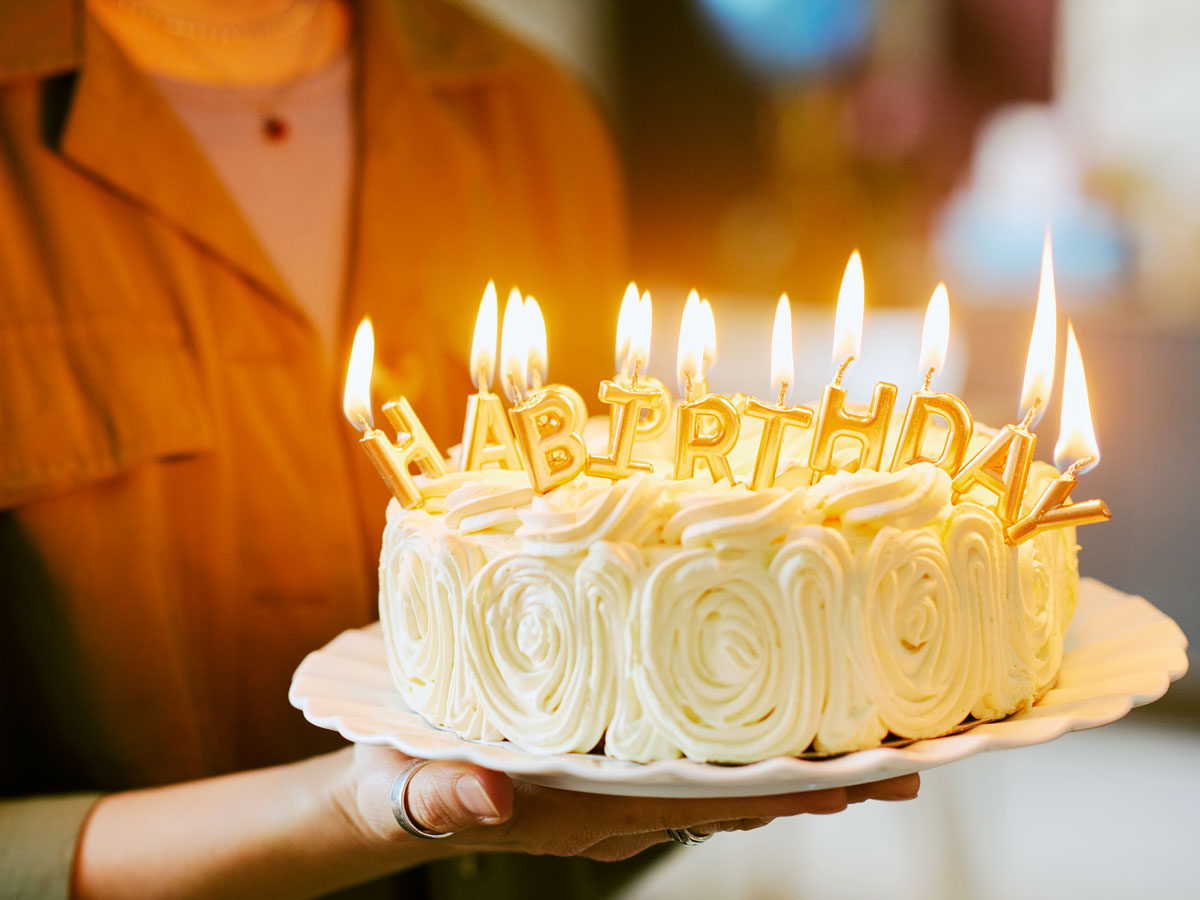 Person holding birthday cake lit with candles