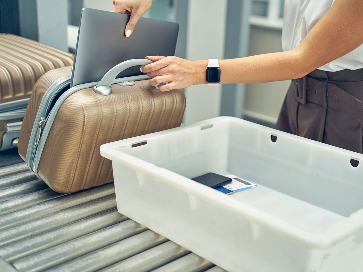 Traveler removing laptop computer from bag for security screening