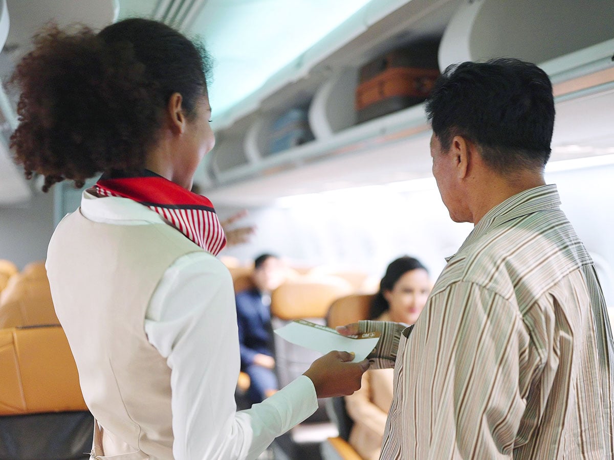 Flight attendant directing passenger to seat on plane