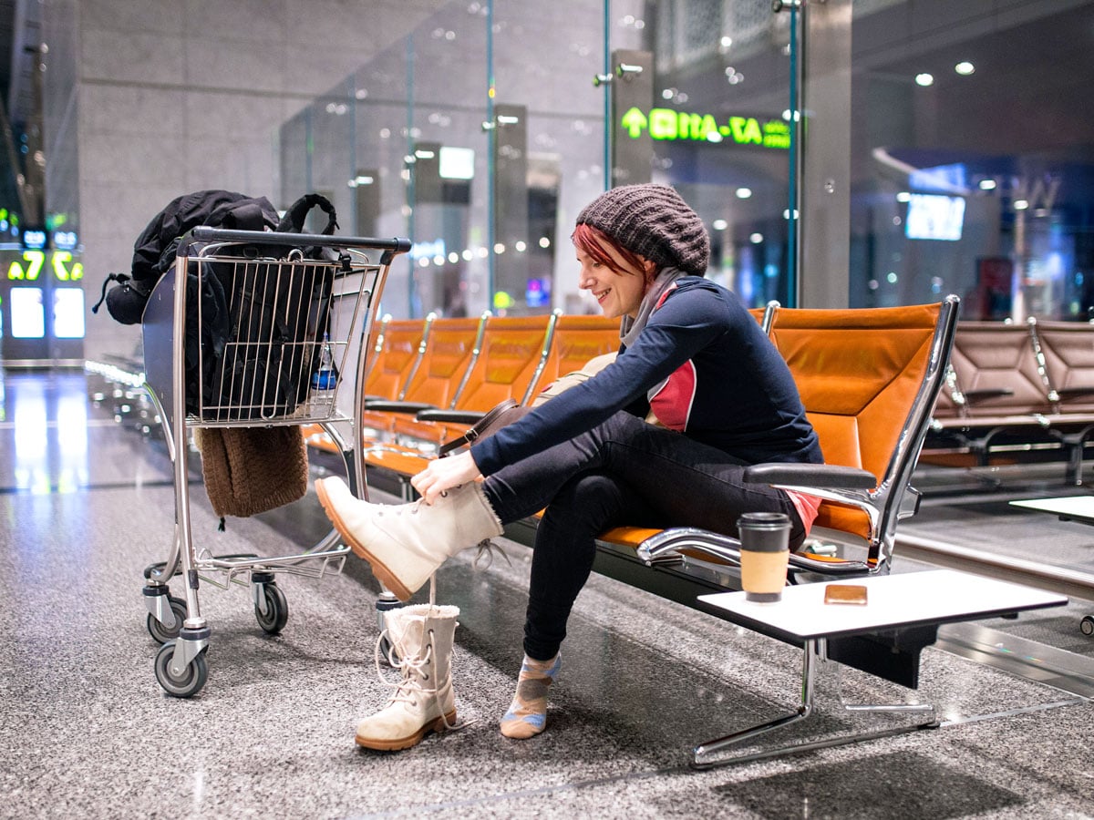 Woman putting on boots in airport terminal