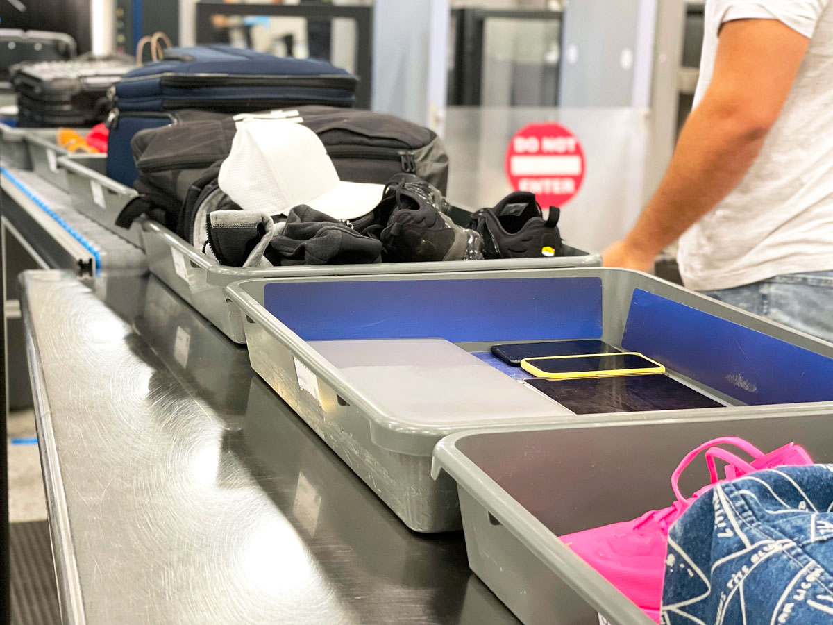 Items in trays on conveyor belt to be scanned in X-ray machine at airport security checkpoint