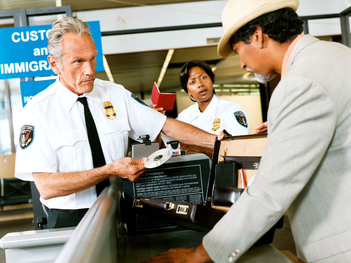 Customs and immigration officer examining contents of a traveler's suitcase