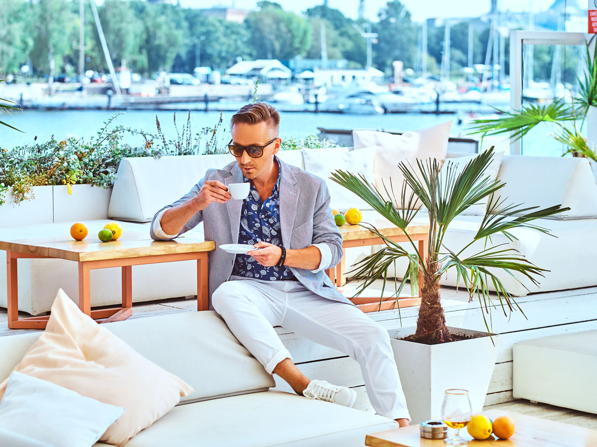 Man sipping coffee on patio beside marina
