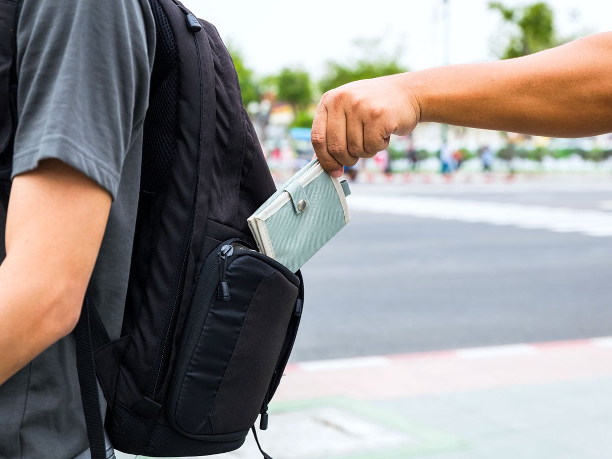 Person taking wallet out of backpack of unsuspecting victim 