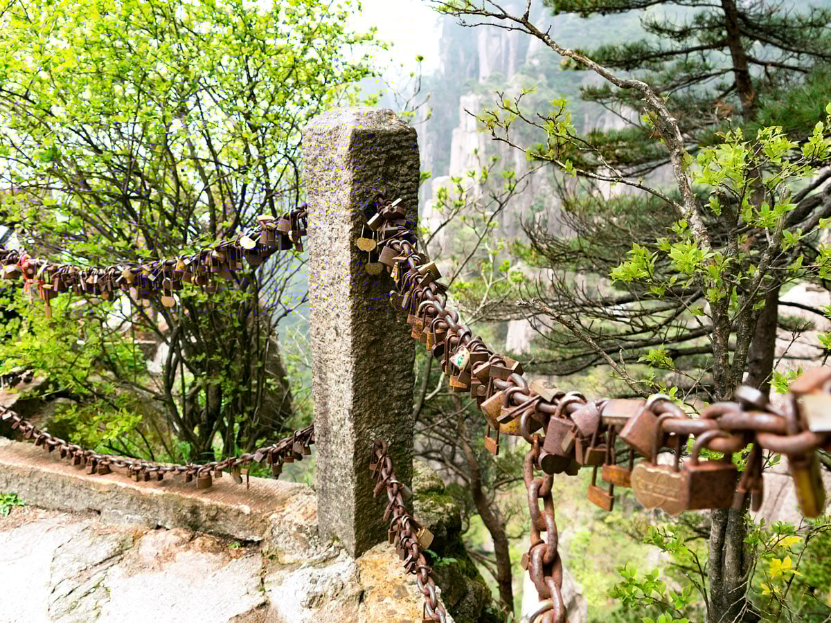 Padlocks attached to railing overlooking Mount Huangshan in China