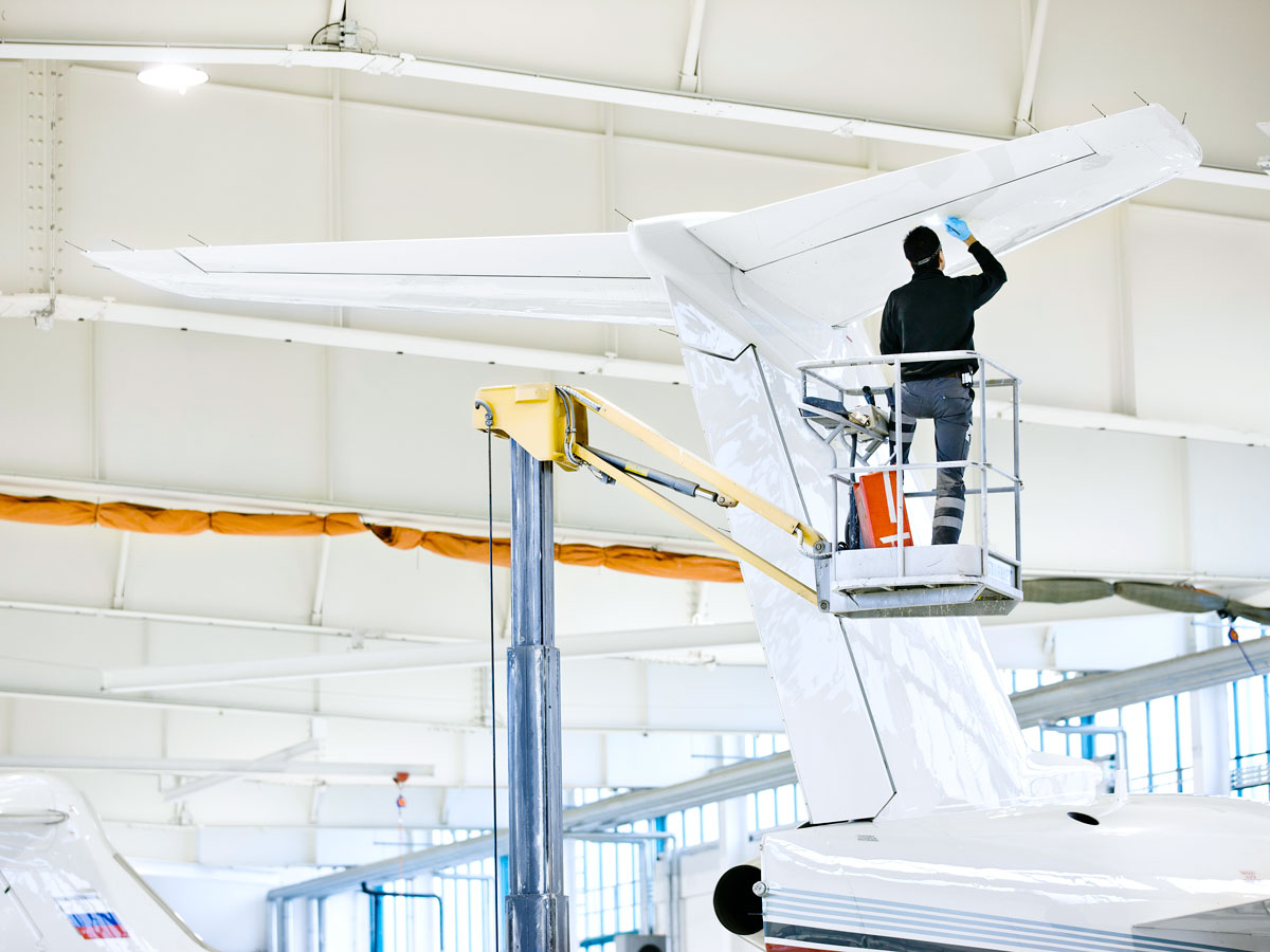Technician painting aircraft tail in hangar