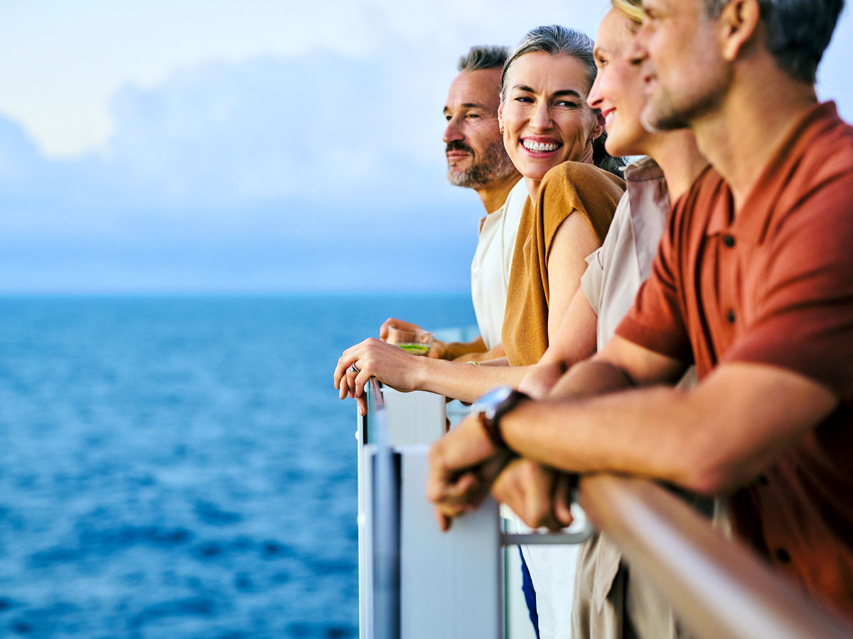Expedition cruise passengers looking out to sea over ship balcony