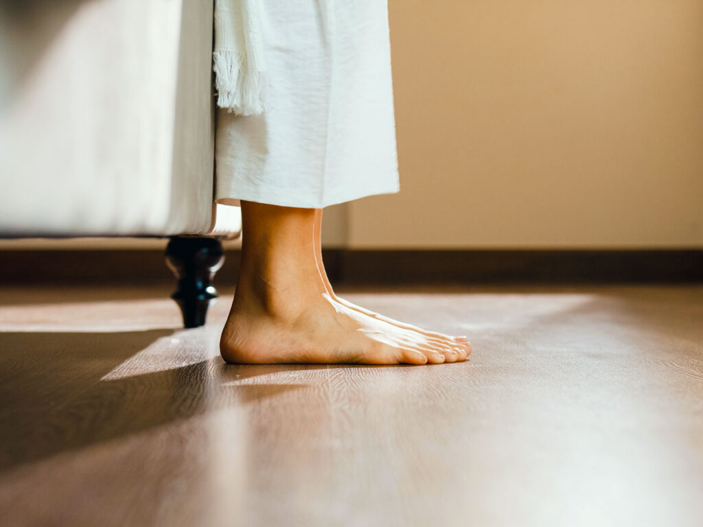 A person's bare feet on hardwood floors