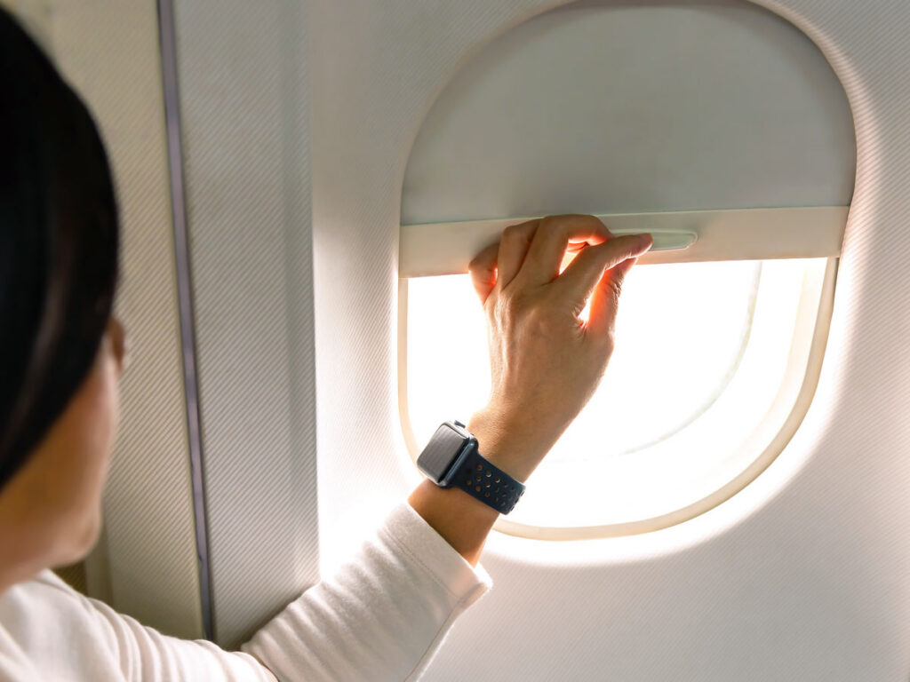 Airline passenger closing window shade