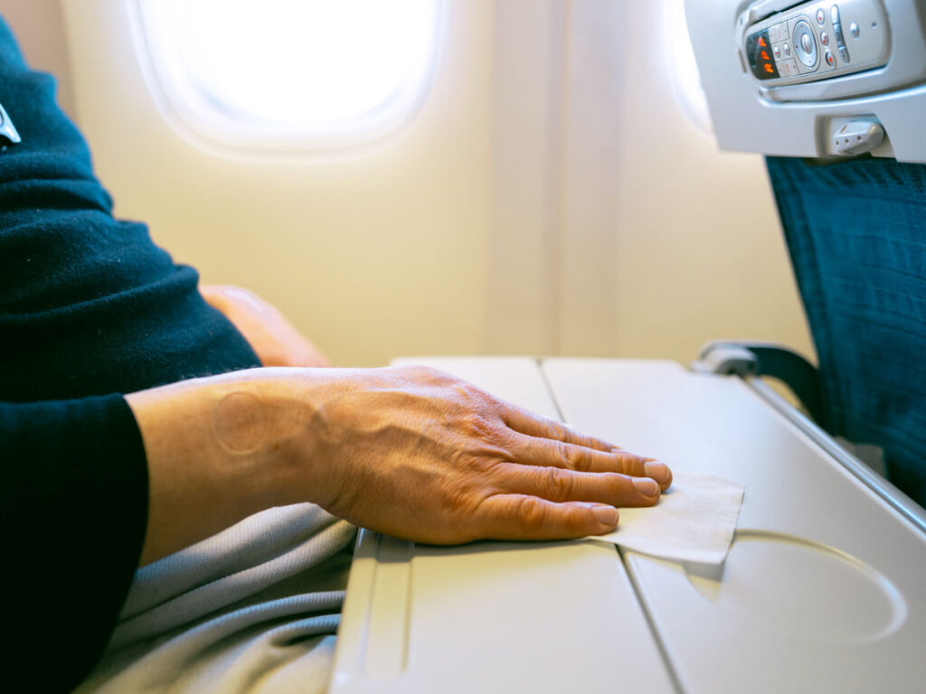 Passenger using wipe to clean tray table