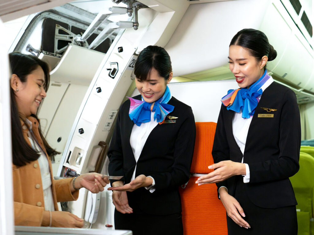 Flight attendants greeting passengers at boarding door