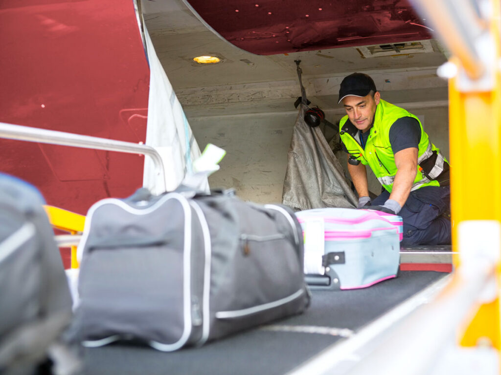 Ramp agent loading baggage into aircraft cargo hold