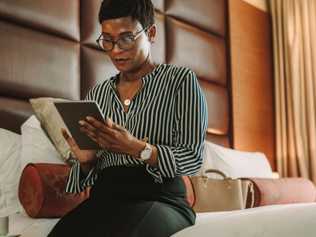 Hotel guest using tablet while sitting on bed