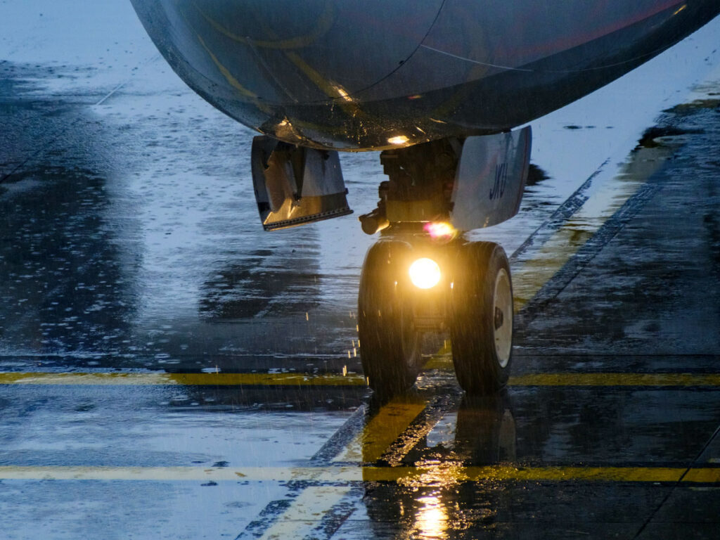 Close-up view of nose wheel on airplane on rainy day